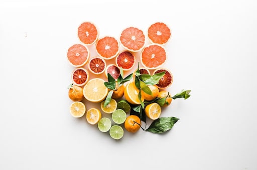 Oranges, lemons, grapefruits, and limes cut in half and photographed against a white surface